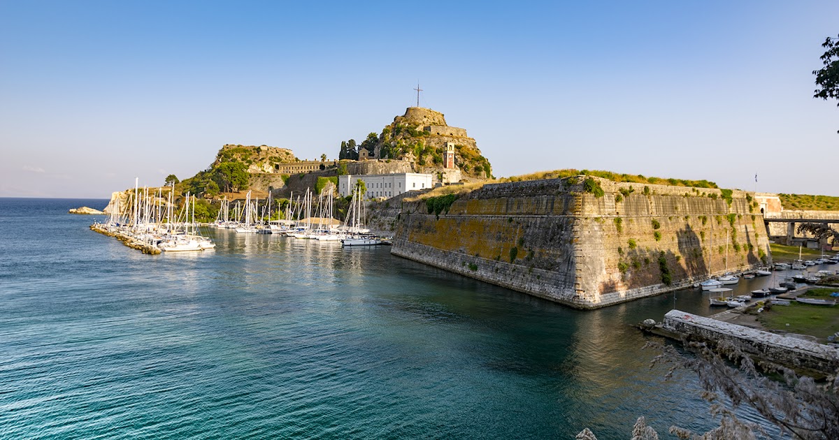 Corfu Old Town fortress and Venetian architecture seen from the sea with lush green hills and Ionian coast in golden afternoon light, Mediterranean island photography