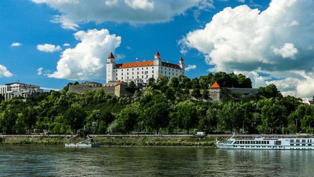 Bratislava Old Town with medieval castle on hilltop above the Danube river and pastel-colored baroque buildings in morning light, Central European heritage photography