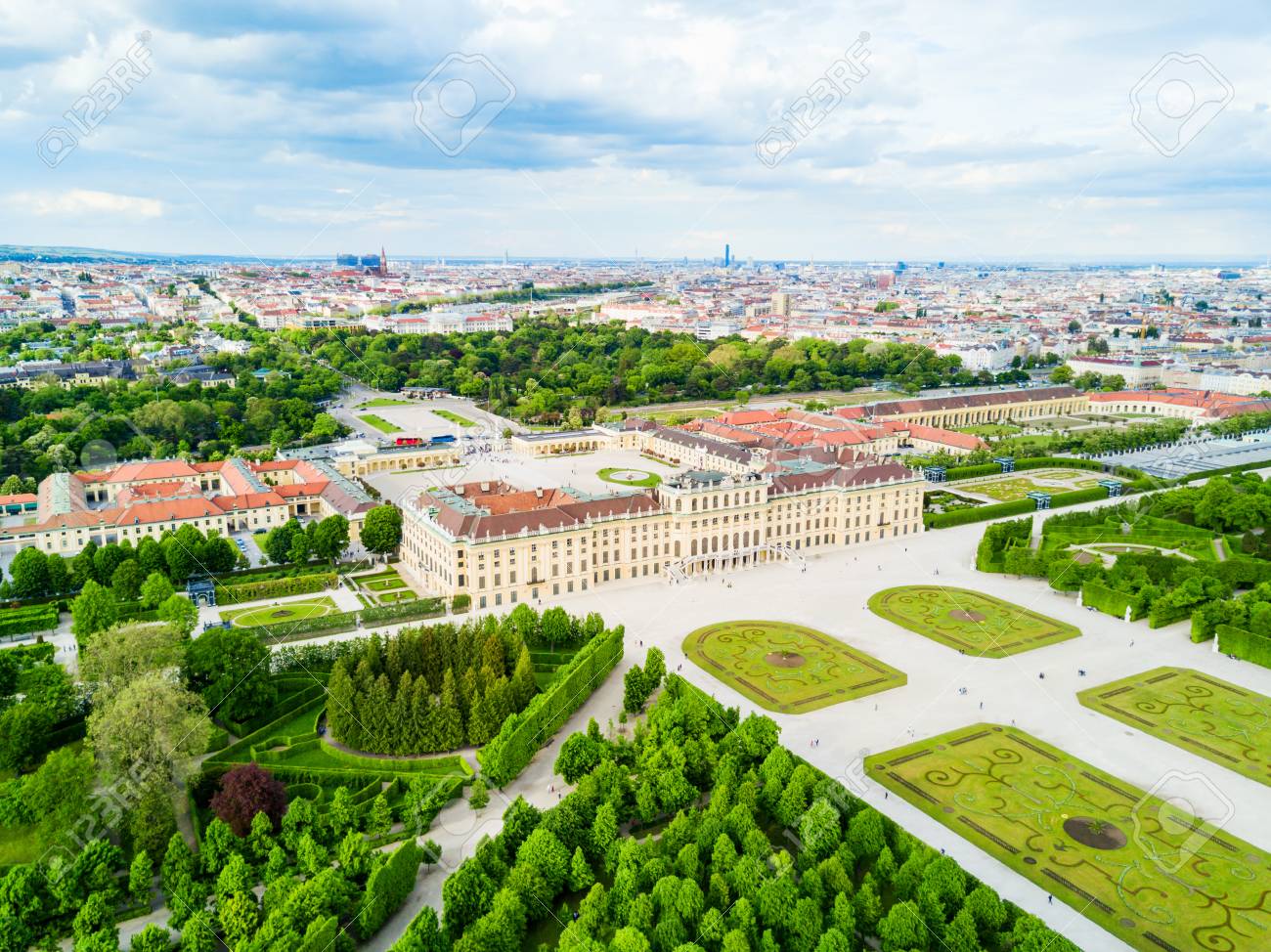 Schönbrunn Palace and formal baroque gardens seen from elevated perspective with Vienna city skyline in background under clear blue sky, Austrian imperial photography