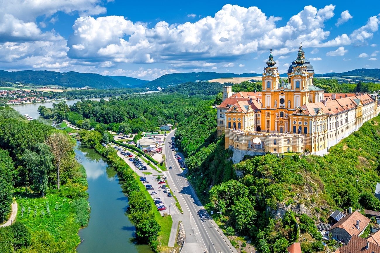 Danube river winding through Wachau Valley with terraced vineyards on steep hillsides and small Austrian village with church spire below, scenic river photography