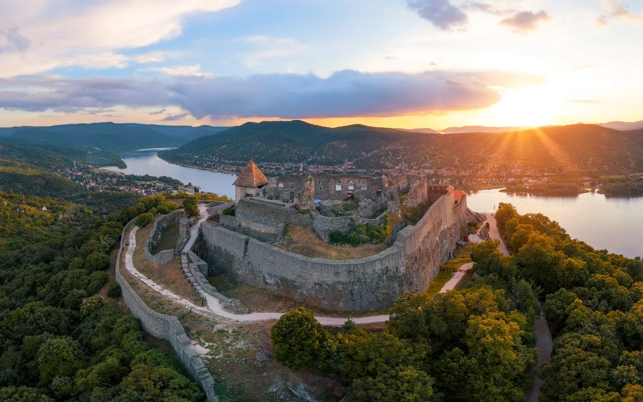 Danube Bend panoramic view from Visegrád castle ruins showing the river curving through forested Hungarian hills in warm afternoon light, scenic river photography