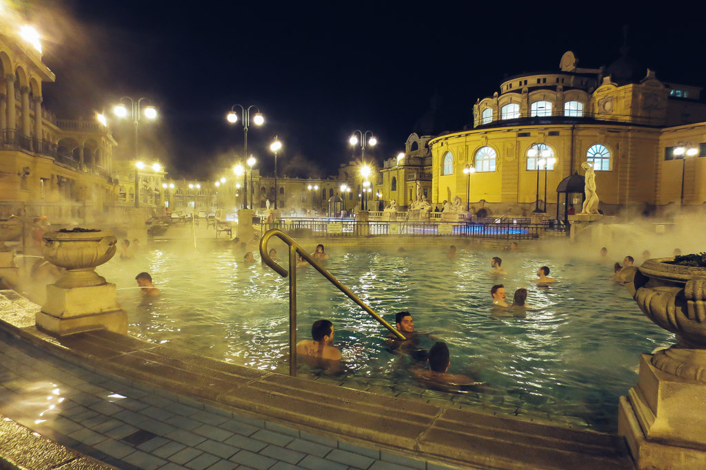 Széchenyi thermal bath in Budapest with steam rising from turquoise outdoor pool and neo-baroque yellow building in early morning light, Hungarian wellness photography