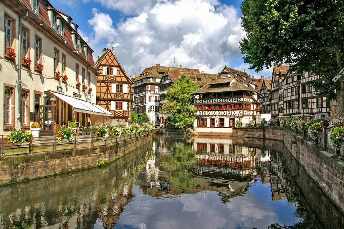 Strasbourg Petite France district with half-timbered houses reflected in canal waters and Gothic cathedral spire in background, Franco-German cultural photography