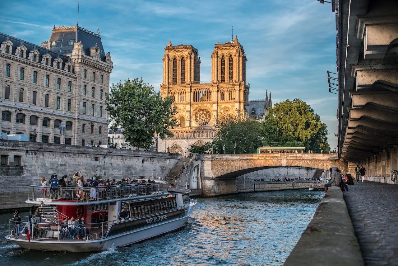 Seine river flowing past Notre-Dame Cathedral and Île de la Cité with stone bridges and tree-lined quays in soft morning light, Paris embarkation photography