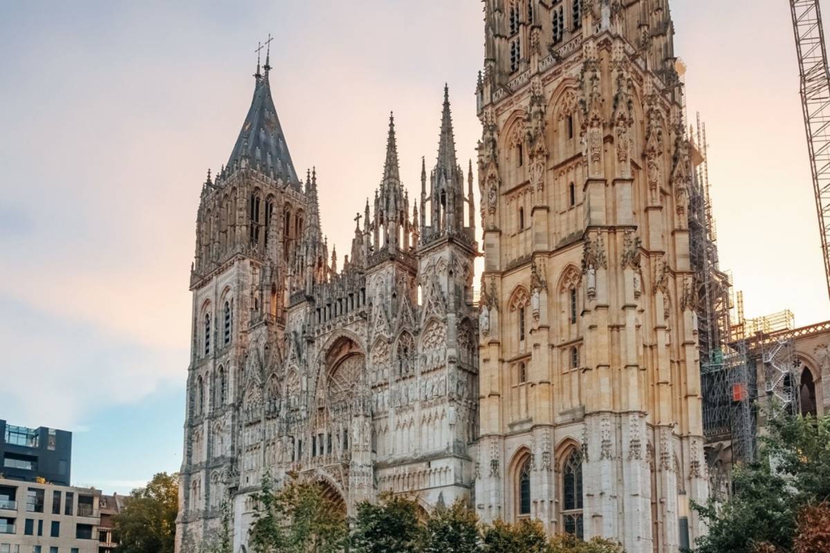 Rouen Cathedral Gothic facade with intricate stone carvings and half-timbered buildings along medieval cobblestone street in soft overcast light, Norman architectural photography