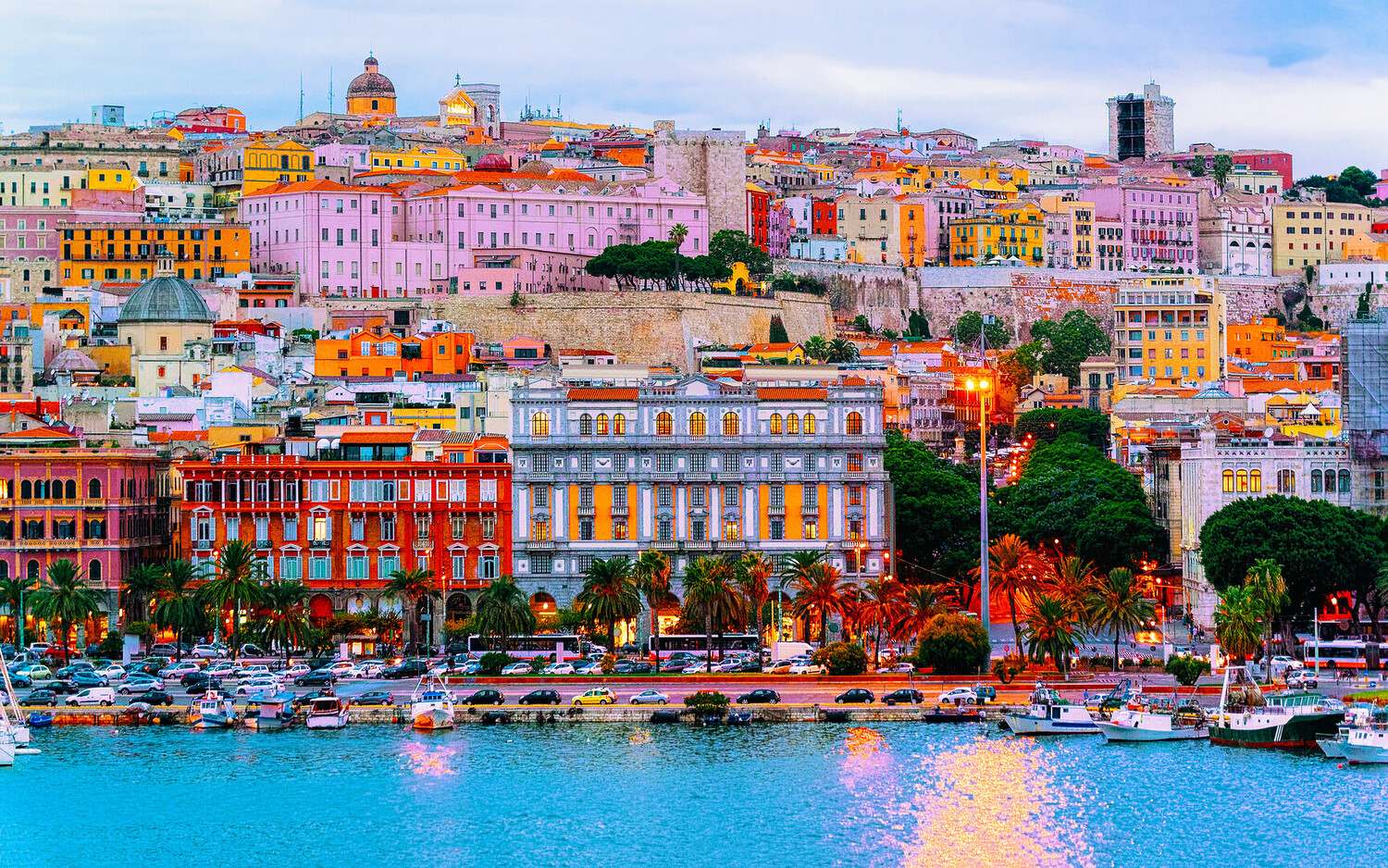 Aerial view of Cagliari old town and harbor in Sardinia with turquoise Mediterranean waters and limestone cliffs in bright afternoon light, island travel photography