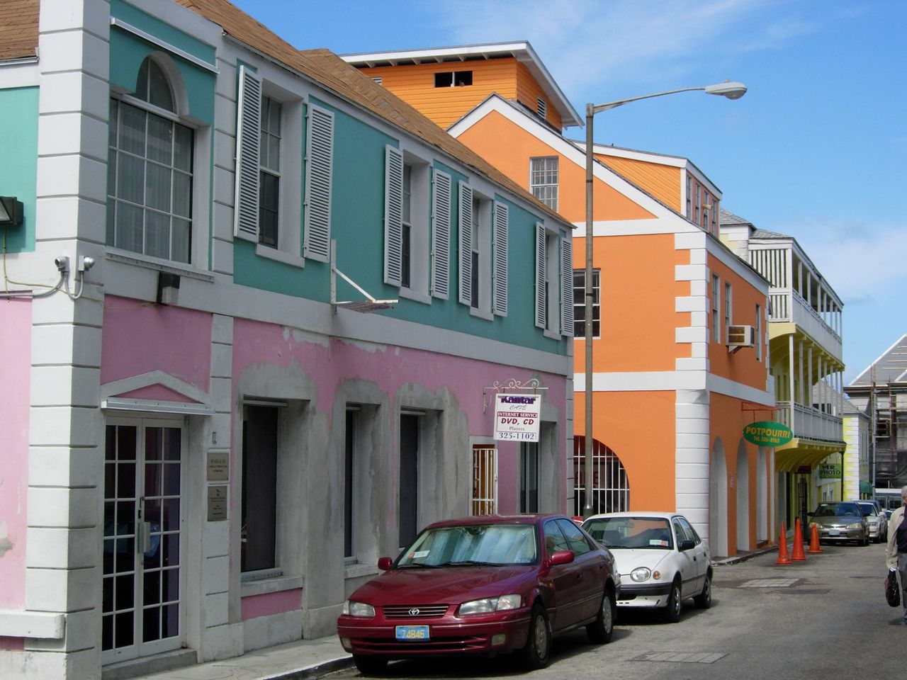 Colorful colonial buildings along Bay Street in Nassau Bahamas with horse-drawn carriage and cruise ship visible in harbor, Caribbean heritage photography