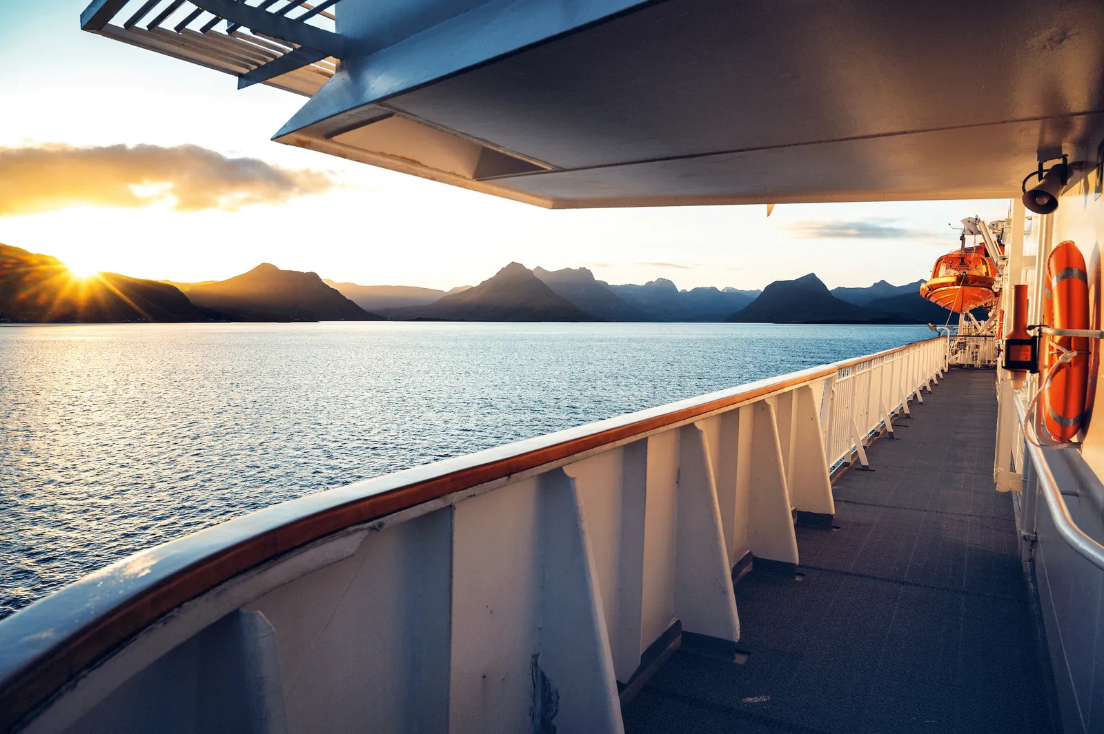 Norwegian coastal landscape at golden hour with rocky islands and lighthouse marking the Arctic Circle crossing, calm sea reflecting warm light against subarctic terrain, expedition photography