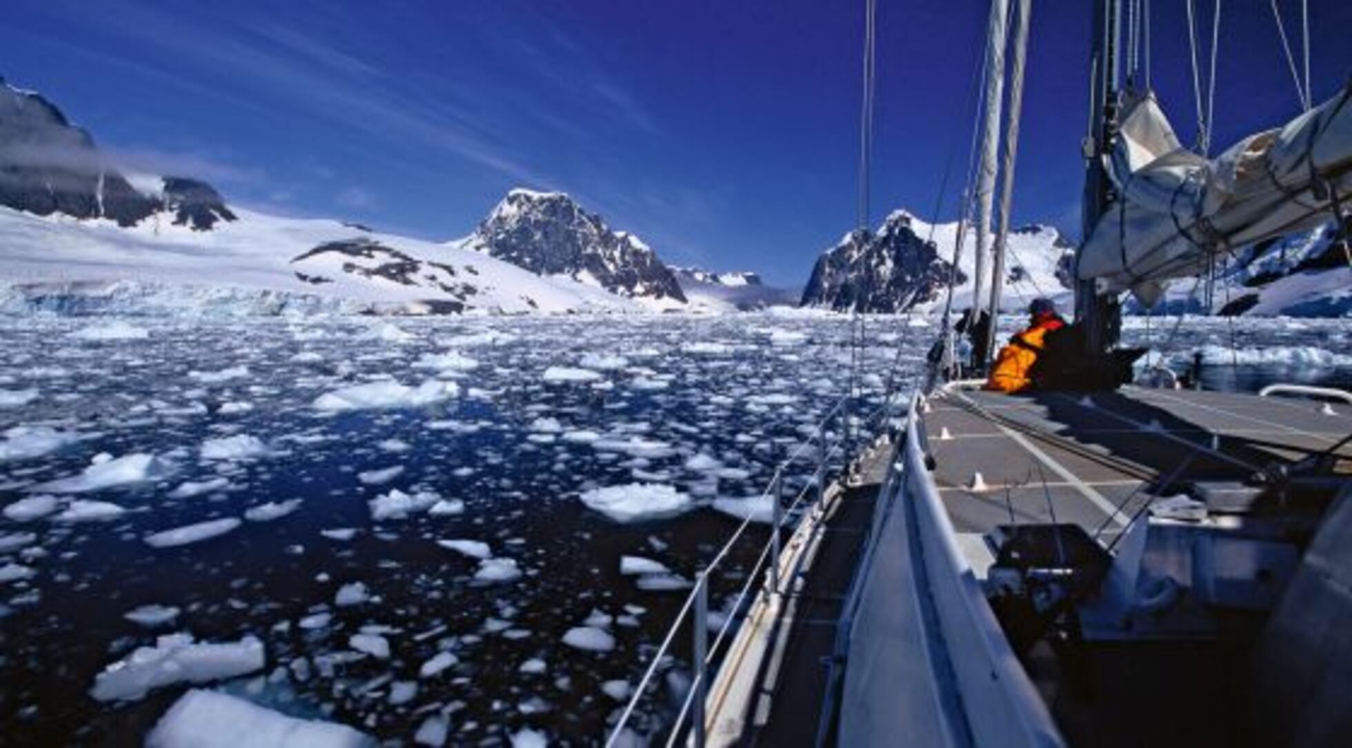 Lemaire Channel Antarctica with towering ice cliffs on both sides framing narrow passage of dark water and expedition ship passing through, glaciers calving into channel, polar landscape photography