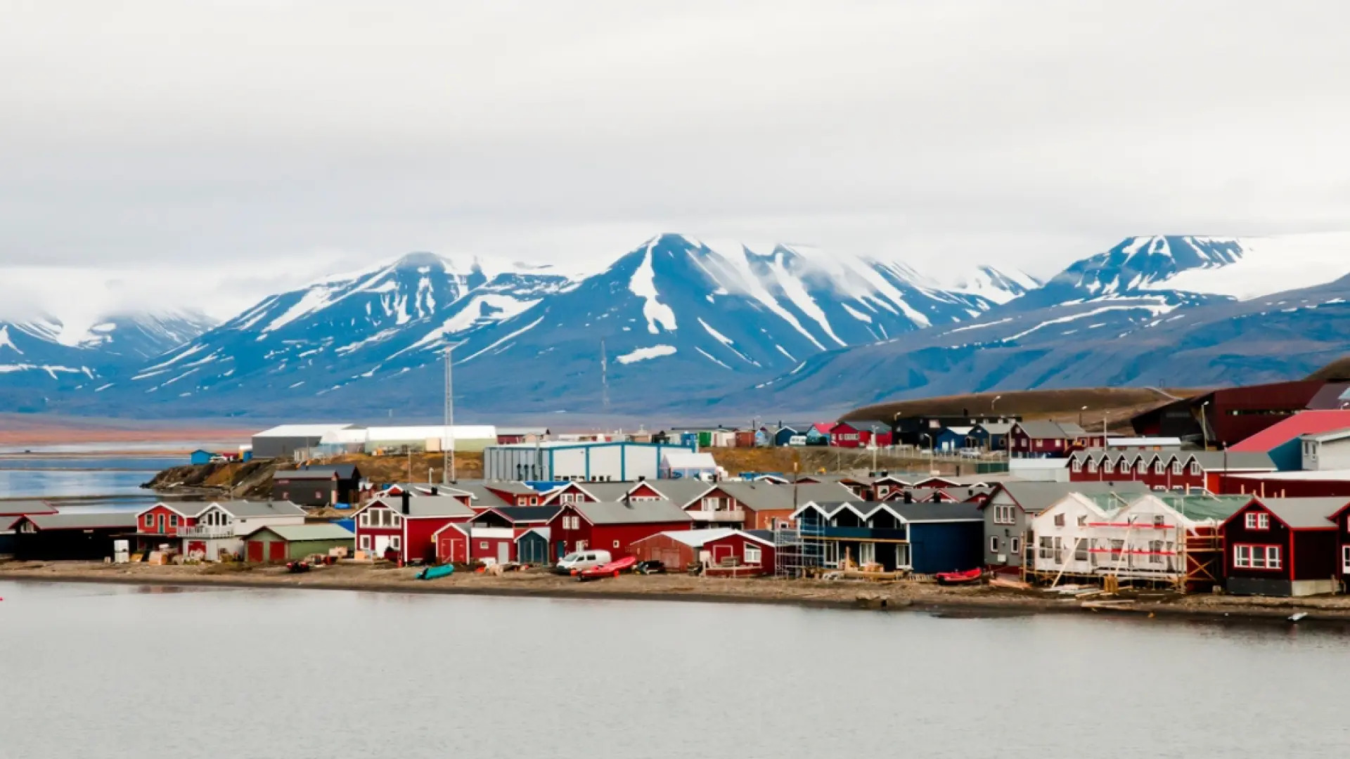 Longyearbyen Svalbard colorful wooden houses against barren Arctic mountain backdrop with expedition ship in harbor under pale midnight sun, northernmost settlement photography