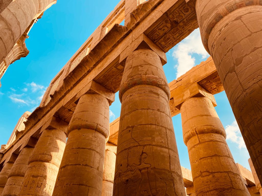 Karnak Temple massive hypostyle hall with towering carved stone columns in warm morning light and hieroglyphic details visible, ancient Egyptian heritage site photography
