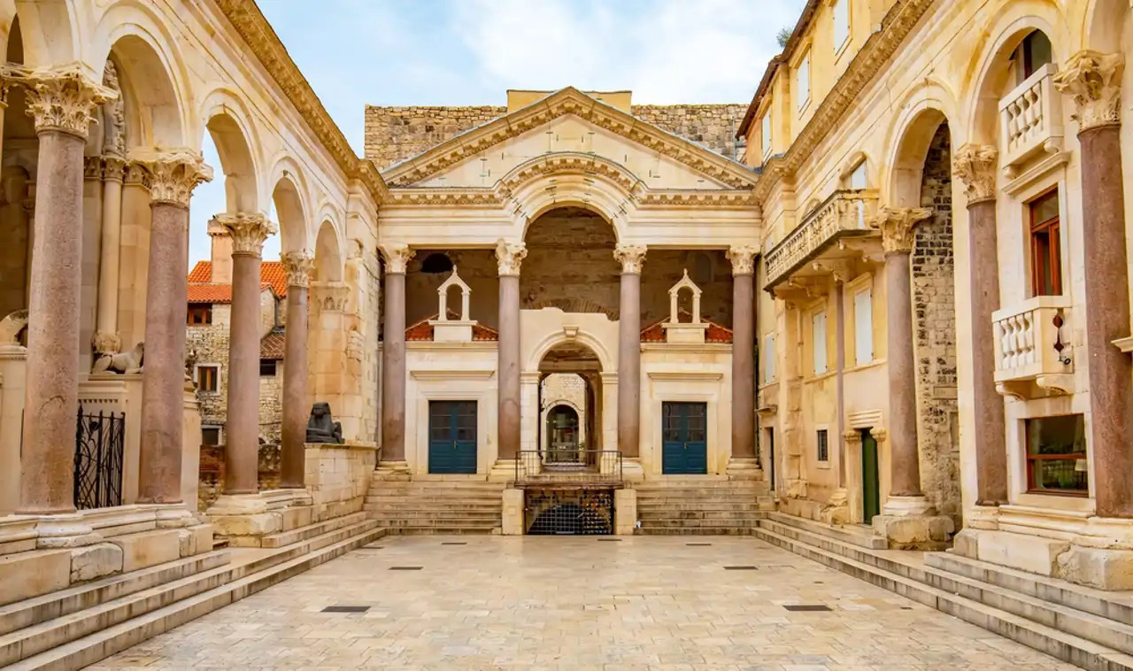Diocletian's Palace in Split Croatia with ancient Roman columns and arches surrounding lively courtyard filled with cafe tables, warm Dalmatian afternoon light, Mediterranean heritage photography