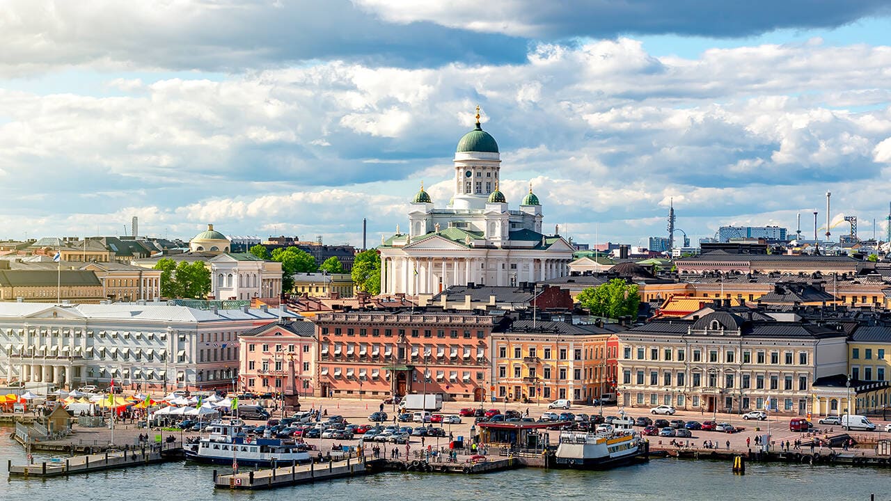 Helsinki harbor waterfront with neoclassical cathedral dome and market square seen from approaching cruise ship with Suomenlinna fortress island visible in foreground, Finnish summer light, Baltic travel photography