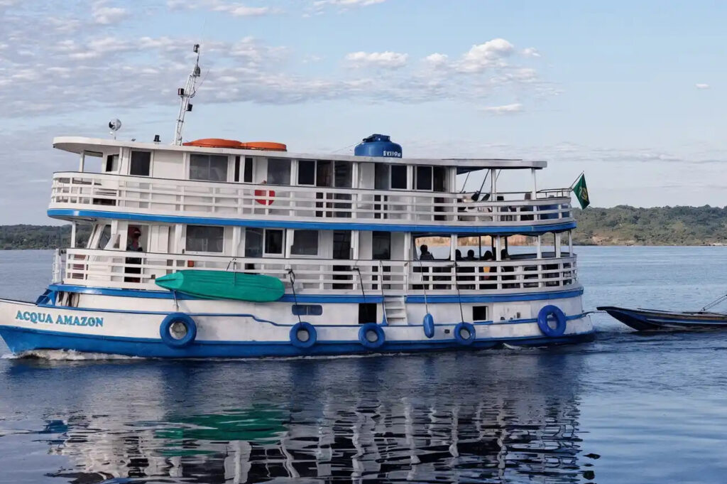 Small expedition cruise ship anchored on the Rio Negro in the Brazilian Amazon at golden hour with dense rainforest canopy re