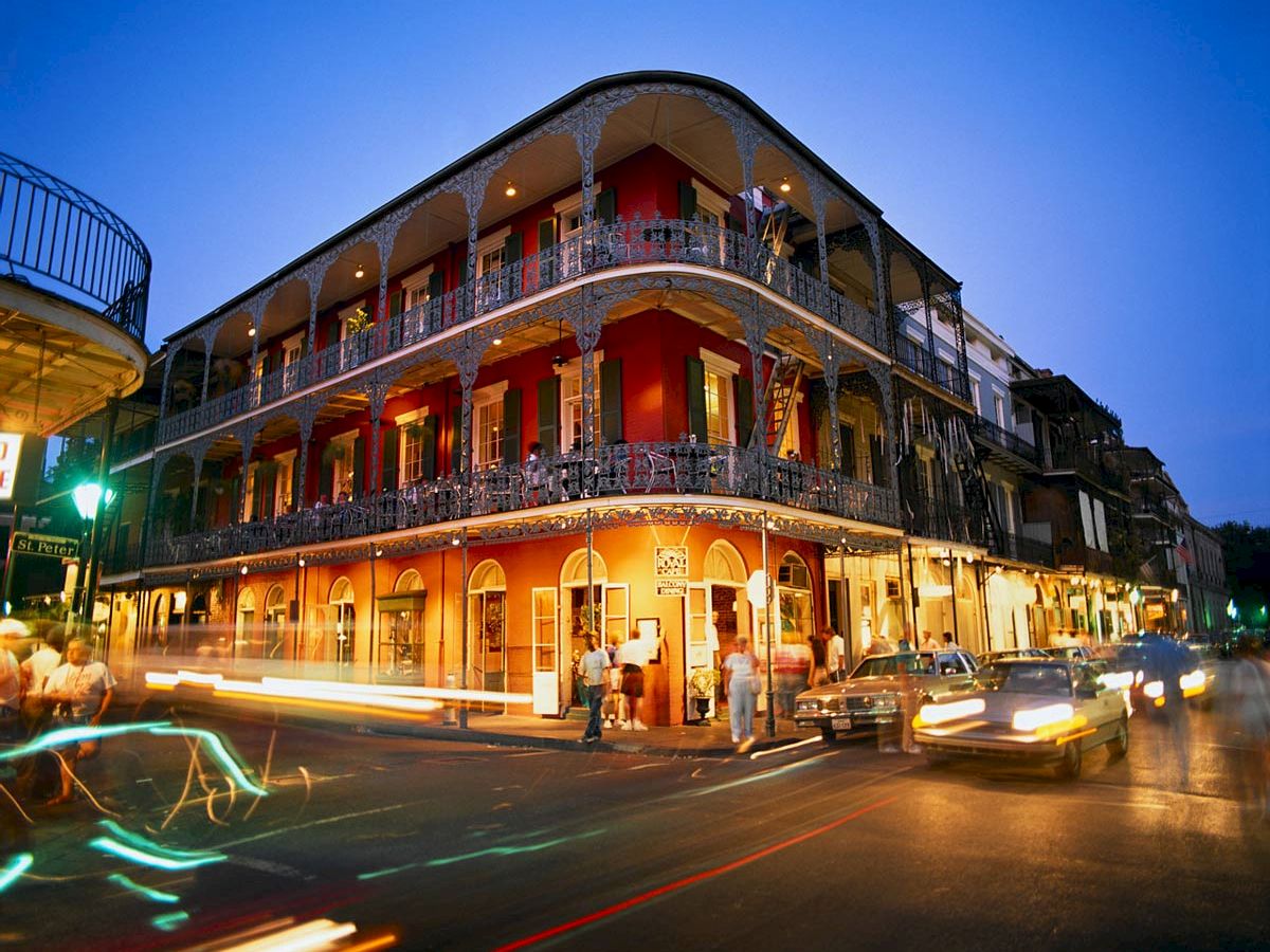 French Quarter New Orleans with iron-lace balconies overhanging narrow street, jazz musicians performing at corner and warm evening light on historic Creole architecture, Southern cultural travel photography