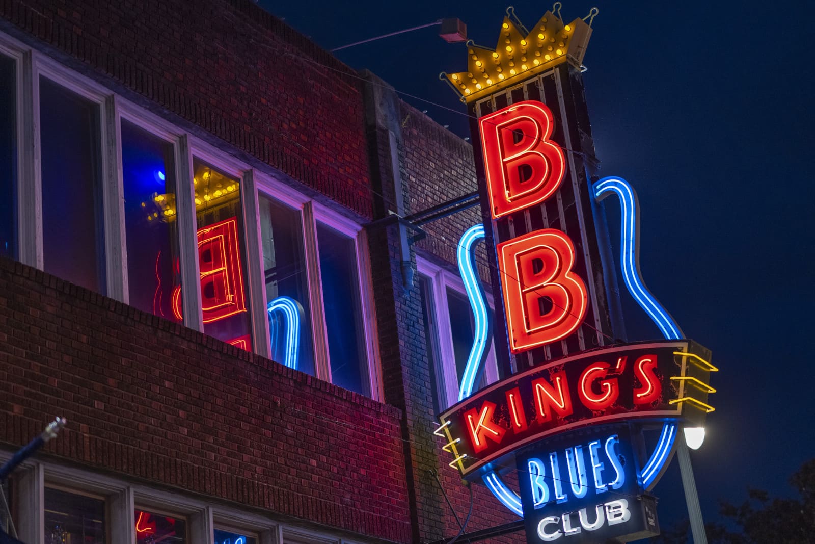 Beale Street Memphis at dusk with neon signs of blues clubs and live music venues glowing along the historic entertainment district, warm evening atmosphere, American music heritage travel photography