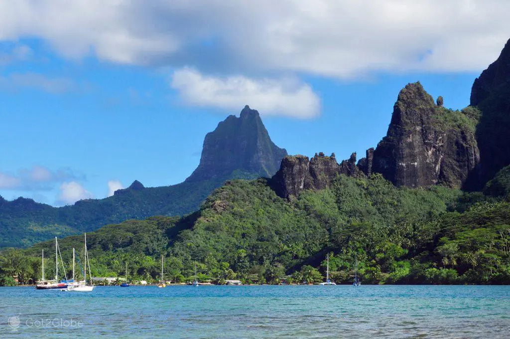 Moorea island dramatic volcanic peaks rising from turquoise lagoon with lush green ridgelines and Cook's Bay visible from small ship anchorage, tropical South Pacific landscape photography