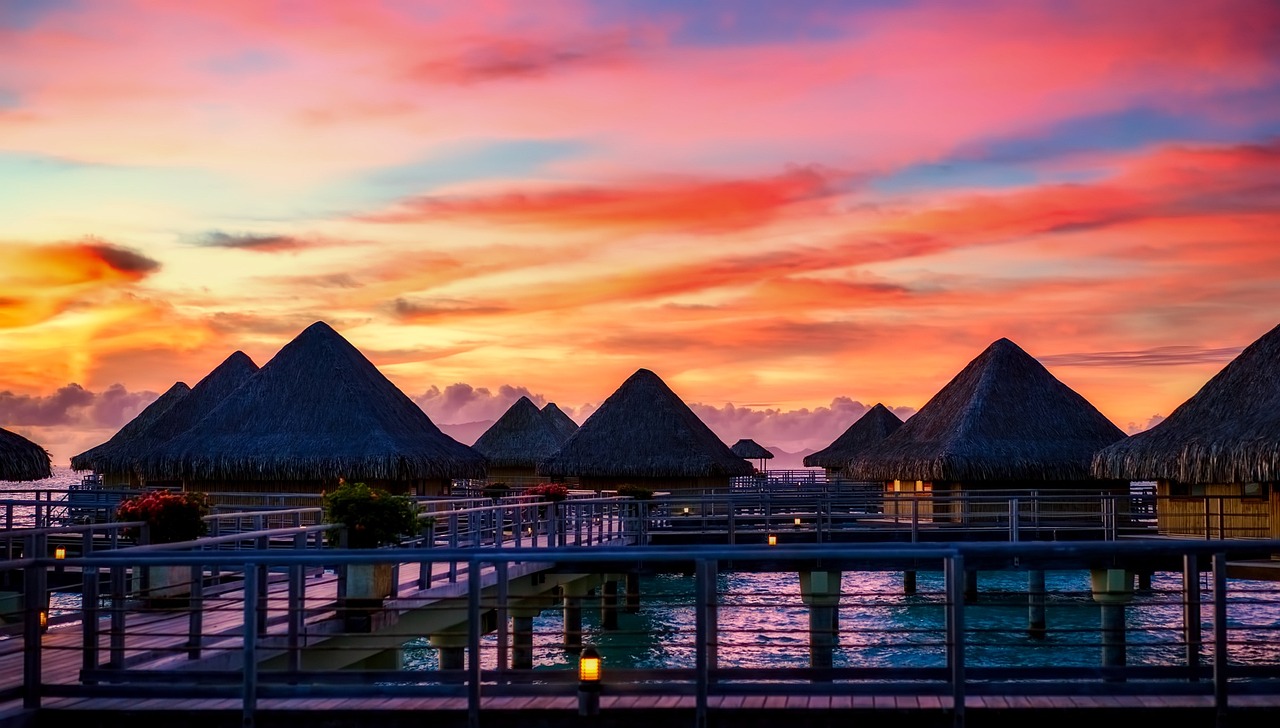 Bora Bora lagoon at sunset with Mount Otemanu basaltic peak silhouetted against warm sky and small cruise ship anchored in turquoise water inside the reef, iconic South Pacific travel photography