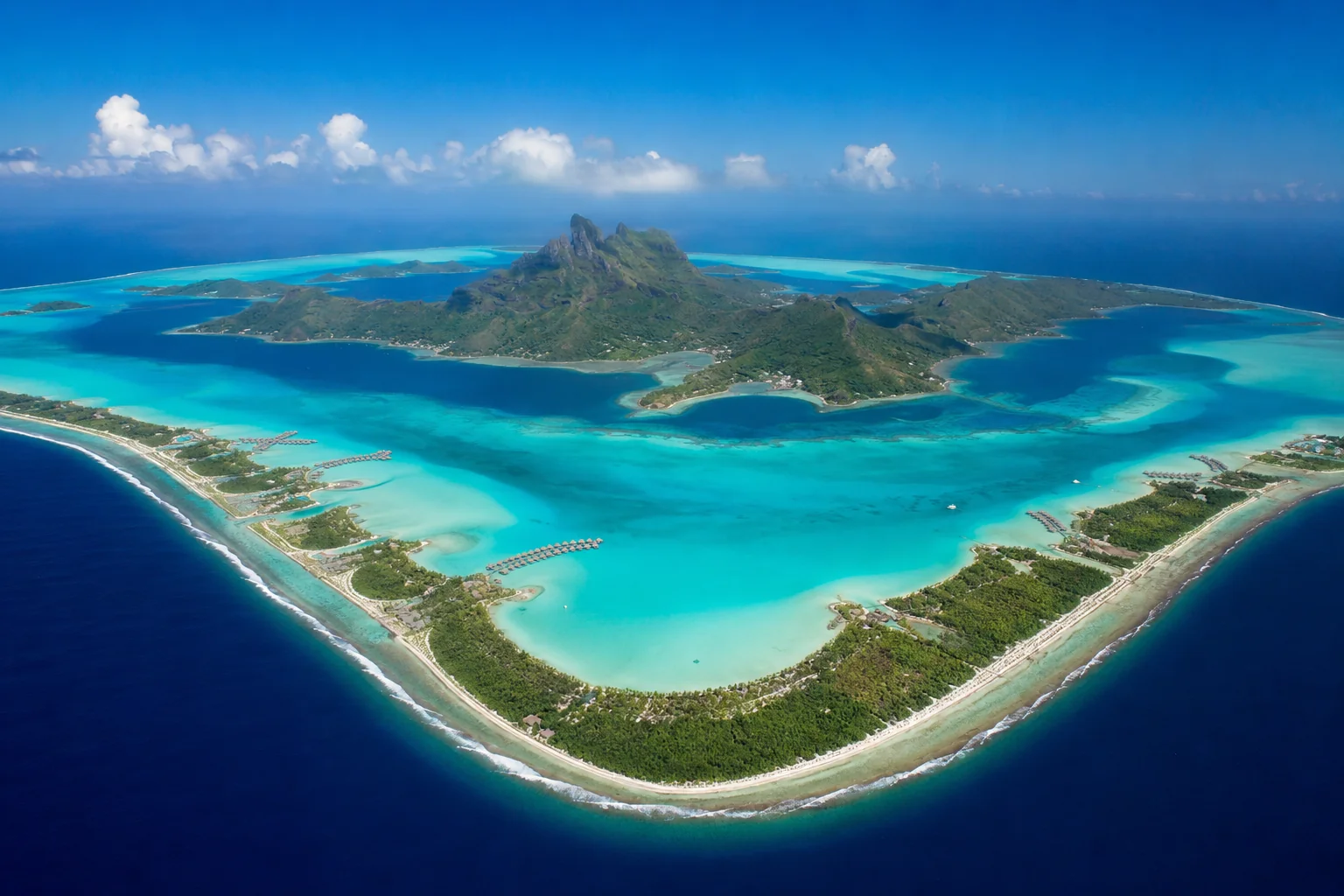 Mount Otemanu volcanic peak rising above turquoise Bora Bora lagoon at golden hour with overwater villas in foreground, scenic landscape travel photography