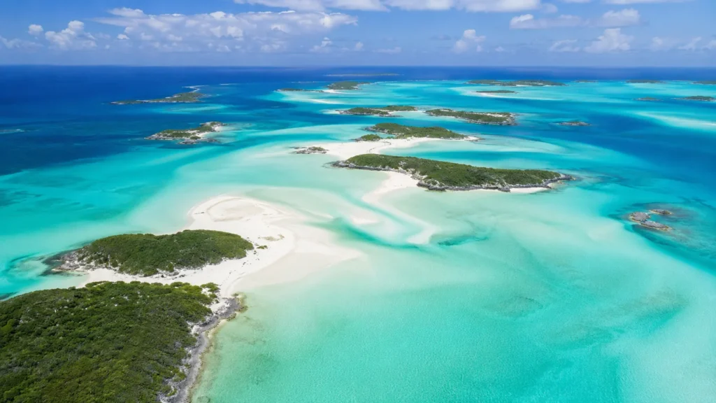 Aerial view of Exuma cays with crystal turquoise water white sandbars and scattered green islands stretching to the horizon,