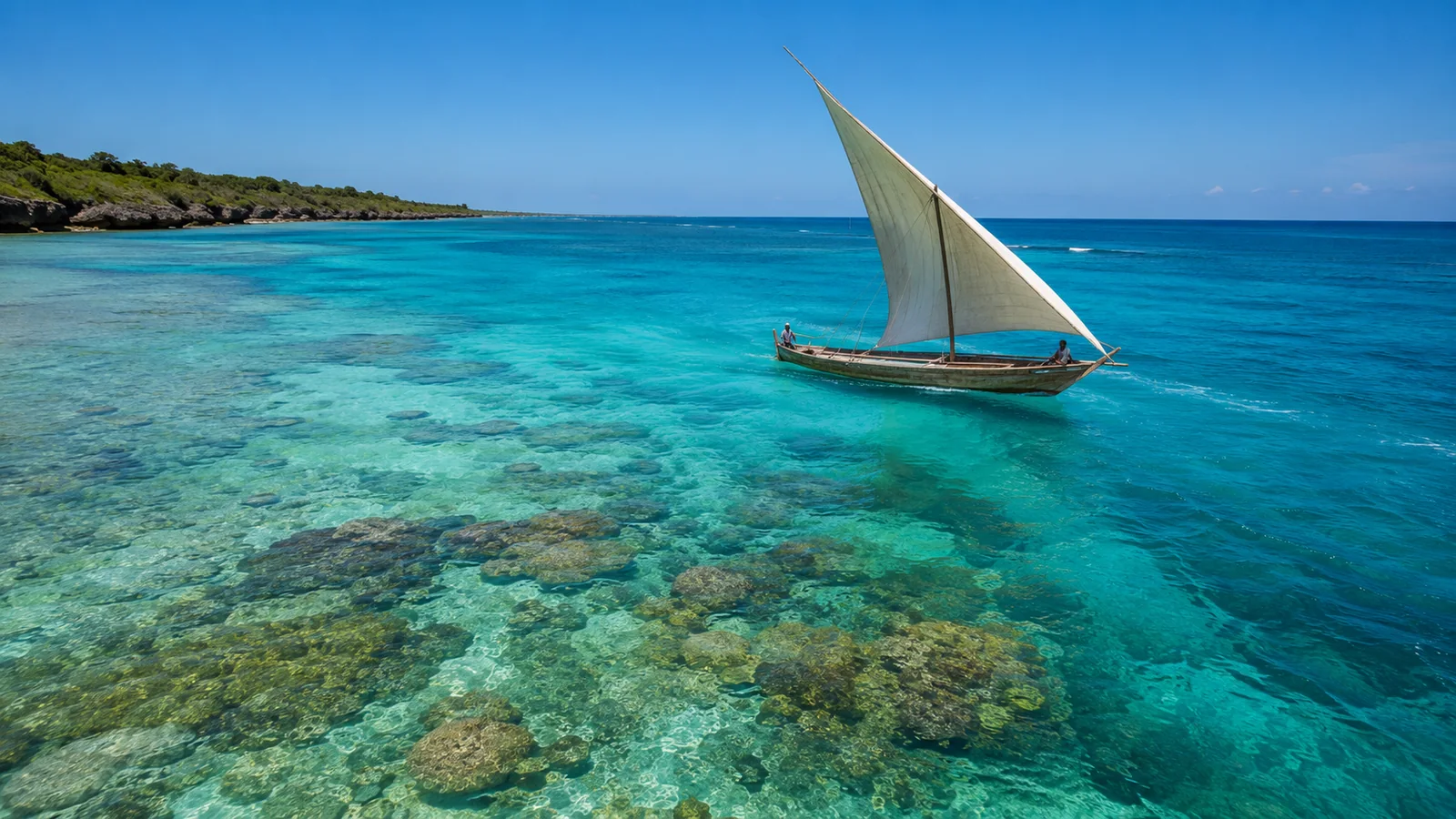 Clear turquoise waters and pristine coral reef off the East African coast at midday with a traditional dhow sailing past under blue sky, Indian Ocean travel photography