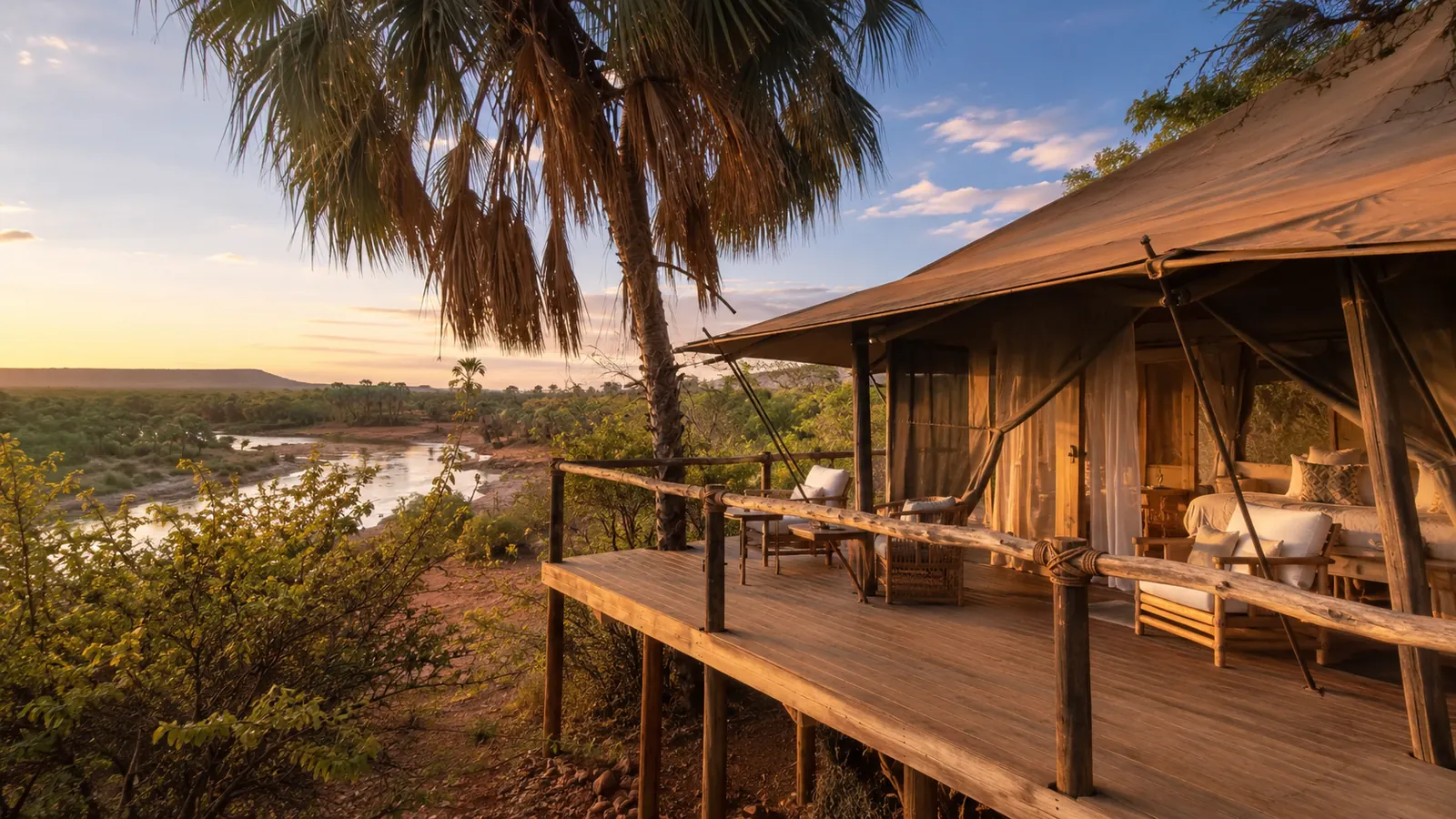 Luxury tented safari suite raised on a wooden platform overlooking the Ewaso Ng'iro river in Samburu with warm sunset light and palm trees, refined lodge photography