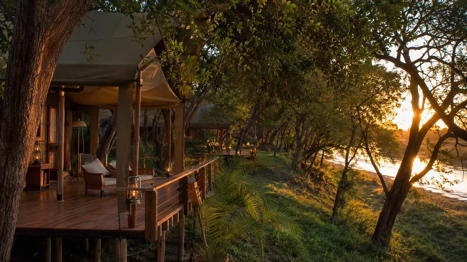 Luxury tented camp nestled among riverine trees on the banks of the Shire River in Liwonde National Park with warm sunset light, exclusive Malawi safari lodge photography