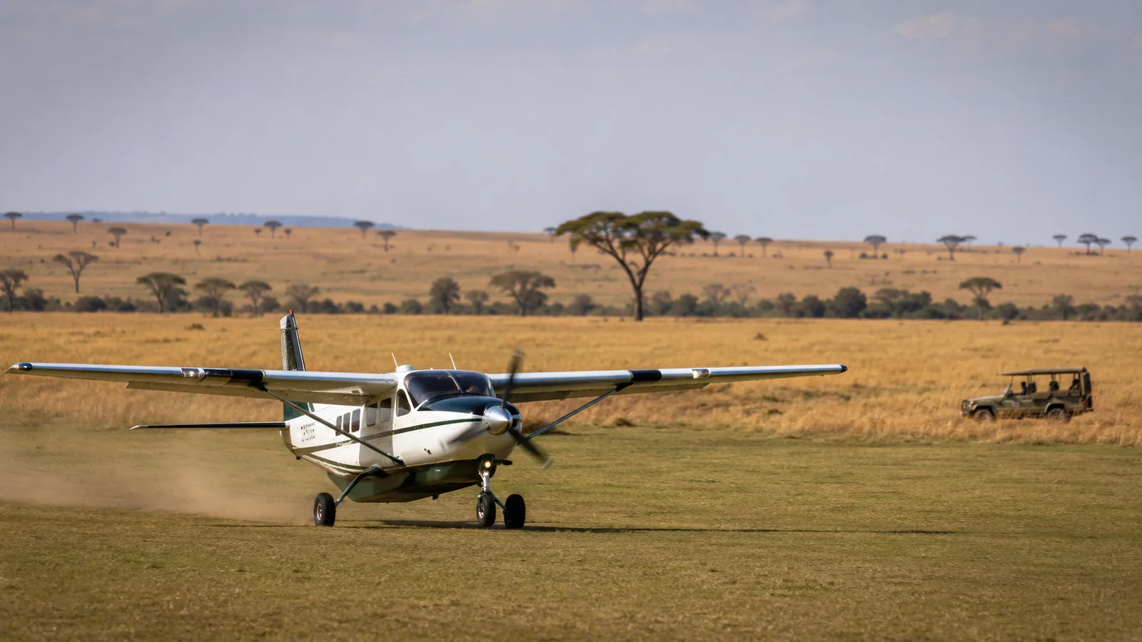 Light aircraft landing on a grass airstrip in the Masai Mara with golden savanna stretching behind, East Africa fly-in safari transfer travel photography