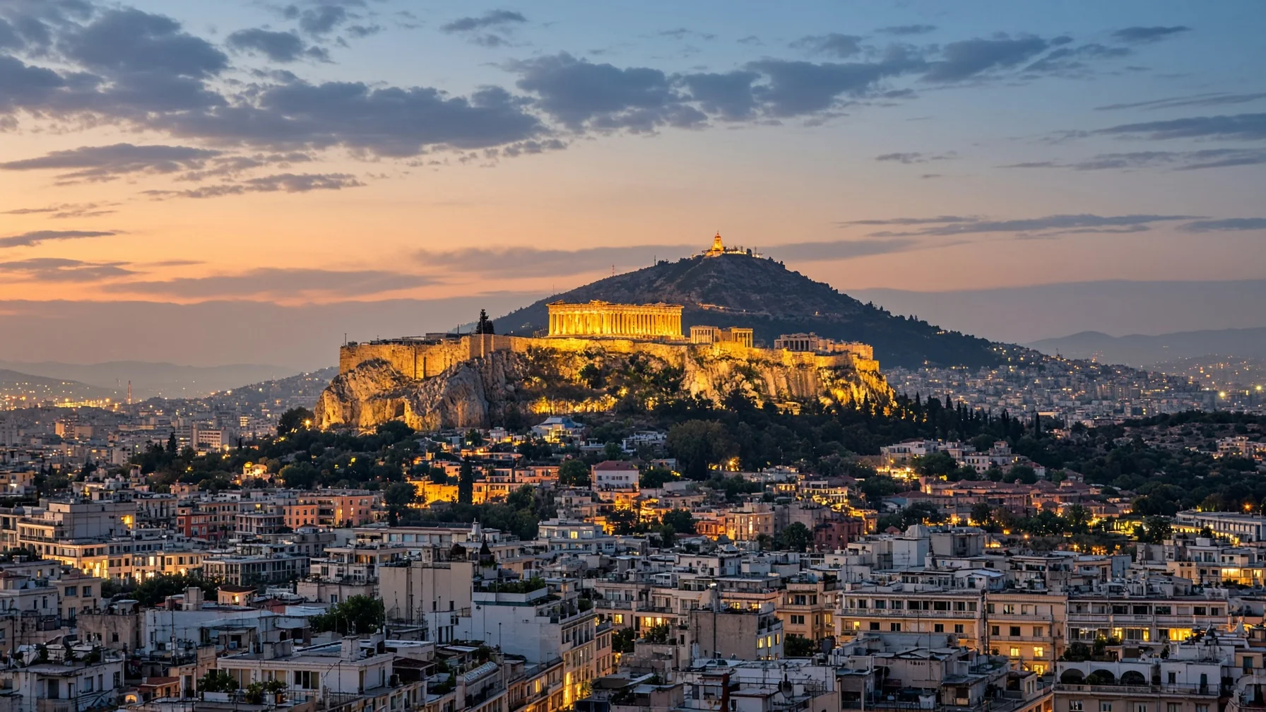Things to do in Athens - the Acropolis lit above the city rooftops at dusk with Lycabettus hill behind and warm evening haze, editorial luxury travel photography