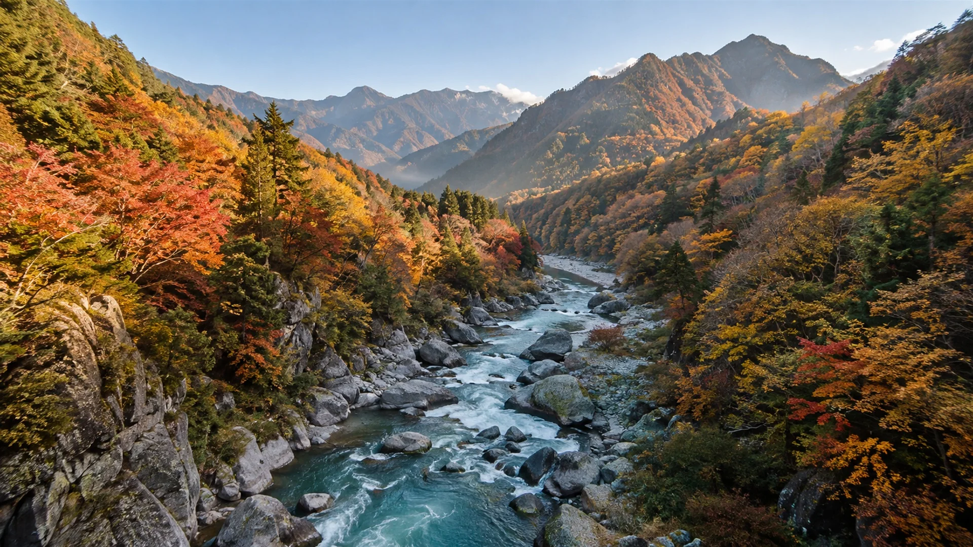 Mountain slopes in red, orange and gold autumn foliage above a winding river gorge in the Japan Alps, crisp clear light, landscape photography