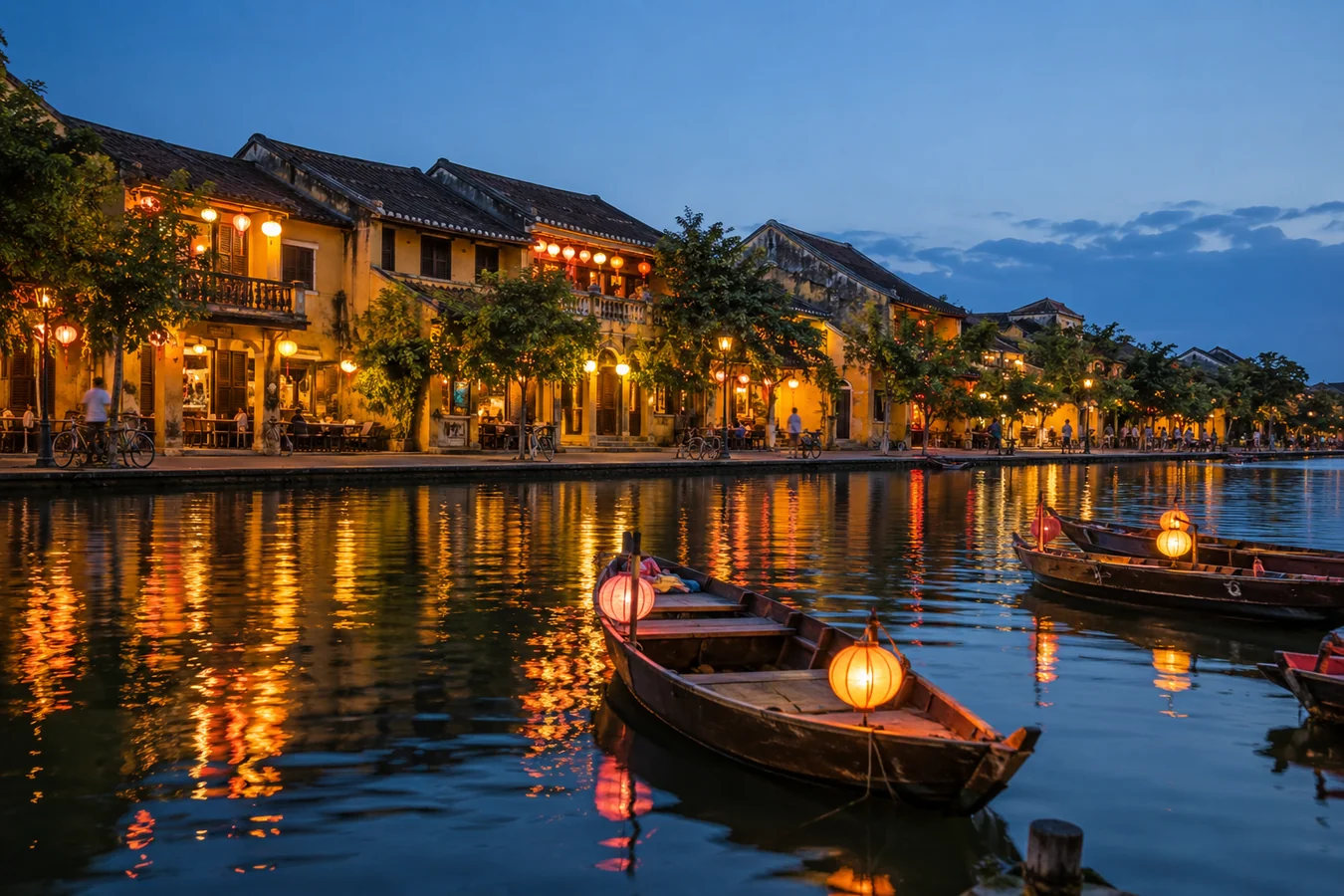 Yellow heritage merchant houses and glowing silk lanterns reflected in the Thu Bon River in Hoi An Ancient Town at blue hour, travel photography