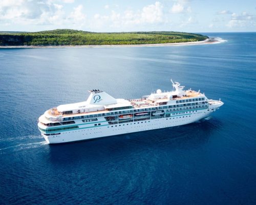 Small cruise ship anchored inside turquoise Bora Bora lagoon with Mount Otemanu volcanic peak rising behind and overwater ree
