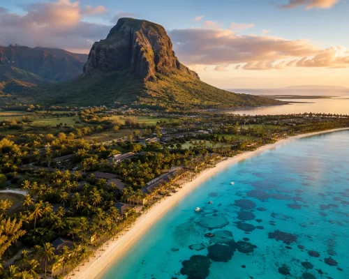 Aerial view of Mauritius coastline with turquoise lagoon white sand beach and green volcanic mountains in background, golden