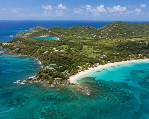 Aerial view of Mustique island with green tropical hillsides white sand beaches and turquoise Grenadine water stretching to t