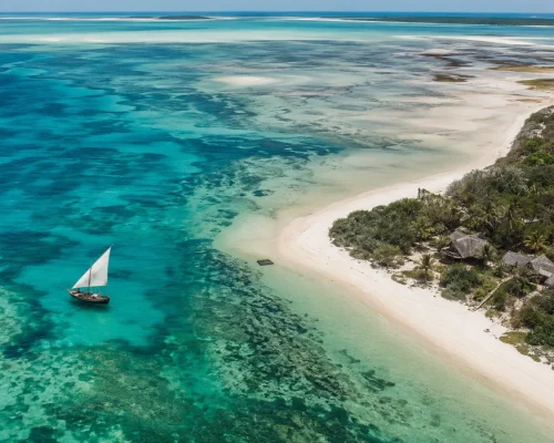 Mozambique beach and safari — aerial view of turquoise sandbanks and a dhow off the Bazaruto Archipelago with a barefoot lodg
