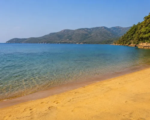 Malawi safari and lake — panoramic view of Lake Malawi's turquoise waters with golden sandy beach and lush green hills behind