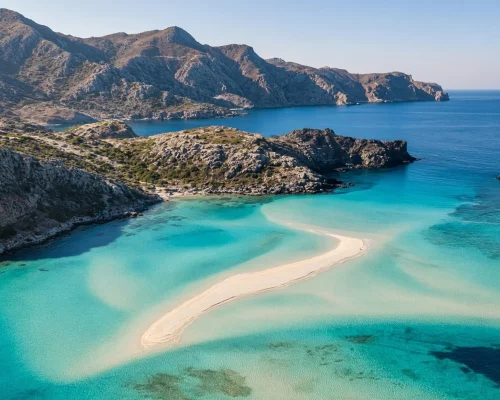 Crete luxury travel - aerial view of a turquoise lagoon with pale sandbars and rugged headlands on the Cretan coast in clear